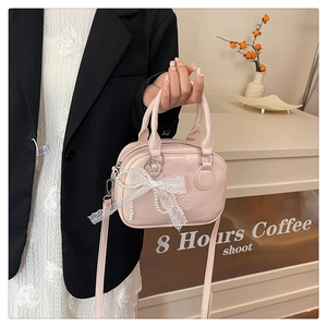 Détail du mini sac bowling rose clair avec nœud en dentelle blanche et chaîne en perles