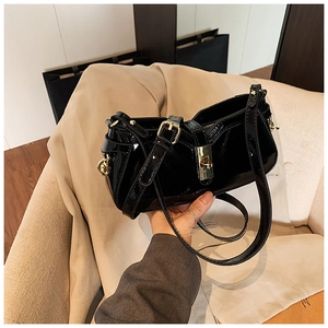Détail d'un sac porté épaule en cuir verni noir avec fermoir doré et bandoulière réglable