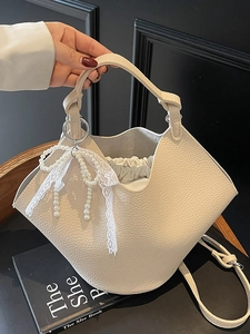 Elegant cream-white litchi grain bucket bag with pearl lace bow charm and crossbody strap
