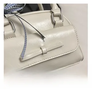 Détail d'un sac Boston blanc avec décoration en nœud de cuir et boucle en métal argenté