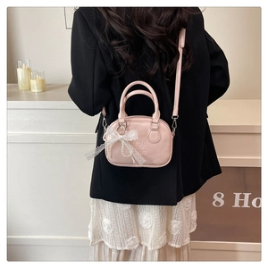 Mini sac bowling rose avec nœud en dentelle et perle porté par un mannequin