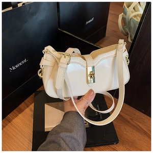 Détail du sac en cuir verni crème avec fermoir rotatif doré et bandoulière ajustable