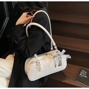 Detail of creamy white Boston shoulder bag with lace bow and checkered ribbon on model