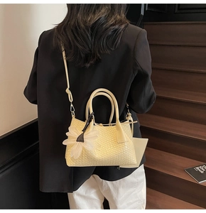 Detail view of cream bucket bag with woven texture and white floral charm on stairs