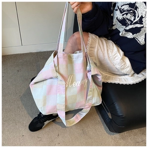 Detail of colorful plaid canvas tote bag with embroidery and woven strap texture