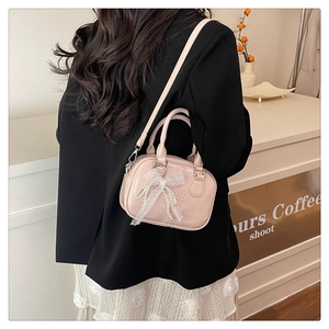 Détail du sac bowling rose en similicuir avec grand nœud en dentelle et perles
