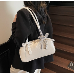 Detail of a creamy white Boston underarm bag featuring lace bows and metal heart charms