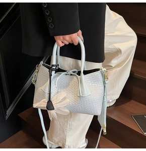 Light blue woven bucket bag with petal charm held by a model on wooden stairs