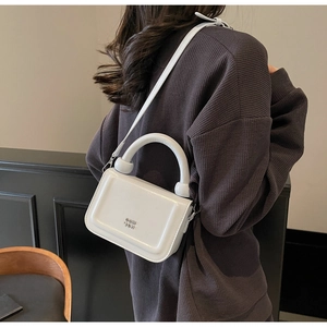 Détail du sac à main blanc structuré avec logo en métal argenté et poignée arrondie