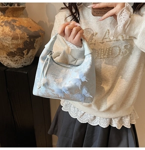 Close-up of light blue jacquard handbag with 3D butterfly embroidery and floral patterns