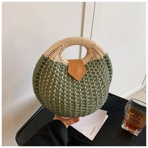 Close-up of green and beige woven circular handbag with round handle and leather buckle