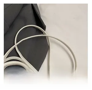 Détail des coutures fines sur la poignée du sac à main crème et les boucles en métal