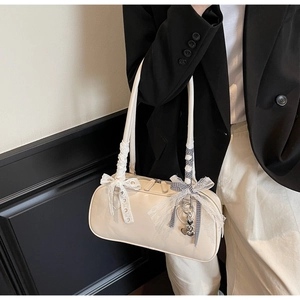 Detail of cream white faux leather bag featuring lace bows and silver bear pendant charm