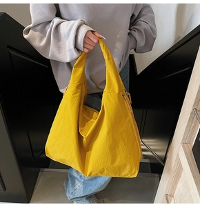 Detail of a bright yellow nylon tote bag featuring unique wrinkled texture and side zipper