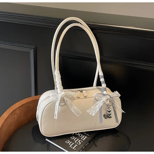 Detail of cream Boston bag with lace bow, checkered ribbon and heart charm on dark base