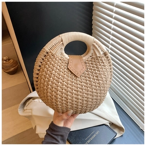 Detail of round straw handbag featuring woven texture and brown leather buckle closure