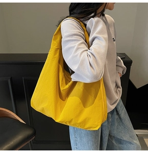 Side view of large bright yellow nylon hobo bag showing the spacious slouchy shape and texture