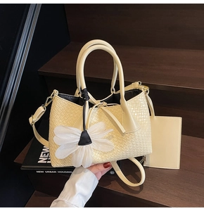 Close-up of beige woven bucket bag with elegant white gauze flower charm on wood steps