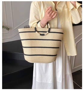 Macro detail of summer straw tote bag with black stripes and circular woven handle