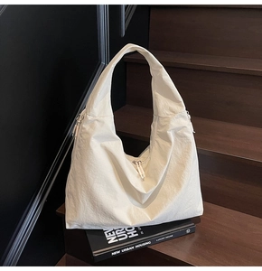 Detail of cream white tote bag with crinkled fabric and zipper on wooden stairs