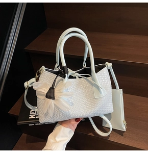 Detail of light blue woven bucket bag with elegant white organza flower charm on dark stairs