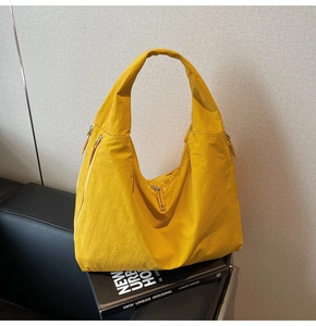 Detail view of bright yellow nylon crescent tote bag with functional zipper pockets