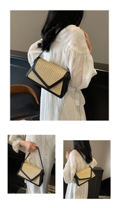 Detail showing natural straw crossbody bag with black leather trim worn by a model