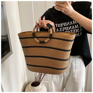 Detailed close-up of a striped handmade straw tote bag with dual-tone woven round handles