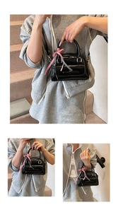 Gros plan d'un mini sac noir brillant orné d'un nœud en ruban à carreaux rouge et blanc