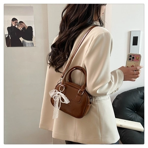 Détail d'un sac bowling en cuir PU marron avec nœud en dentelle et texte embossé