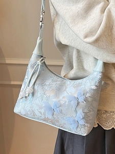 Elegant light blue hobo bag with floral embroidery and 3D butterfly details on model