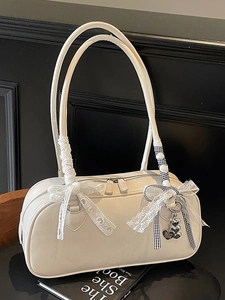 White patent leather Boston shoulder bag with lace bow and heart charm on black background