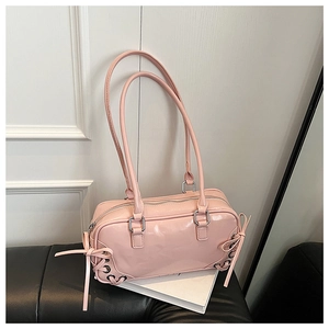 Dettaglio della borsa in pelle verniciata rosa con lacci, fiocco e zip d'argento