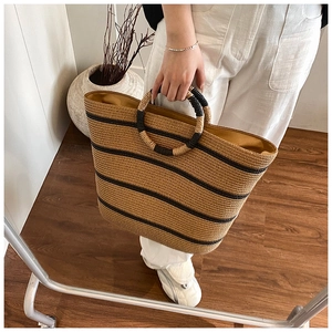 Detail of hand-woven straw tote with striped pattern and distinctive round handles