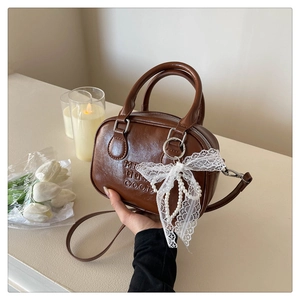 Détail du sac bowling marron foncé en similicuir avec nœud en dentelle et perle