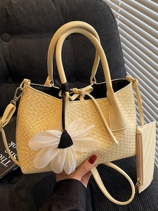 Beige woven bucket bag with floral charm and mini pouch in a lifestyle setting