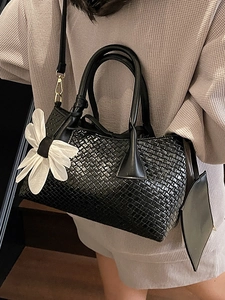 Elegant black woven bucket bag with white flower charm and detachable shoulder strap