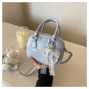 Détail du sac bowling en cuir bleu clair avec nœud en dentelle blanche et perles