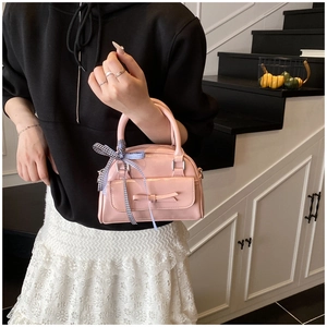 Gros plan d'un sac à main rose brillant avec un nœud et un ruban de soie à carreaux bleus