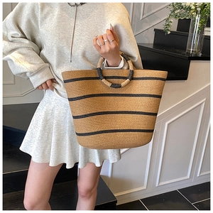 Detailed view of striped woven straw tote bag with round handles and spacious bucket design