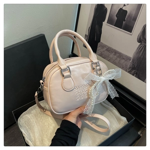 Détail du sac bowling rose avec lettres embossées et charm nœud en dentelle délicat