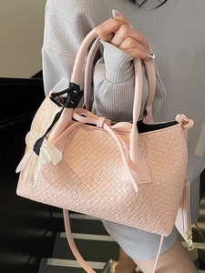 Pink woven bucket bag with bow detail and flower charm for elegant commuter style