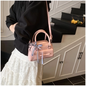 Détail d'un sac à main rose en cuir avec nœud décoratif et bandoulière réglable