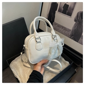 Détail du sac bowling blanc avec lettres en relief et nœud en dentelle et perles