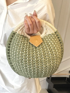 Handwoven green and cream straw bag with circular handles and leather detail