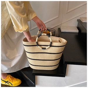 Detail of hand-woven straw bag with black stripes and unique circular double handles