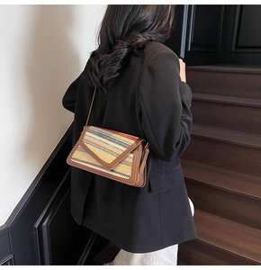 Close-up of rainbow straw woven crossbody bag with brown leather trim and V-flap cover