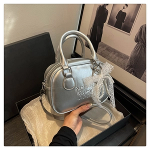 Détail du sac à main argenté avec nœud en dentelle et pendentif perle en boîte cadeau