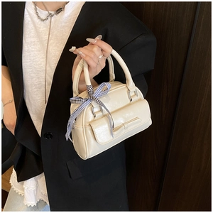 Gros plan d'un mini sac à main crème avec un nœud et un ruban à carreaux bleus sur l'anse