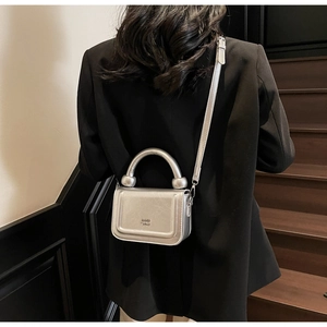Mini sac bandoulière argenté métallisé porté par un mannequin dans un intérieur chic